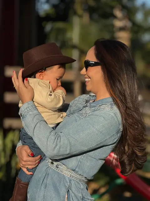 Mãe sorrindo com o filho de chapéu no colo